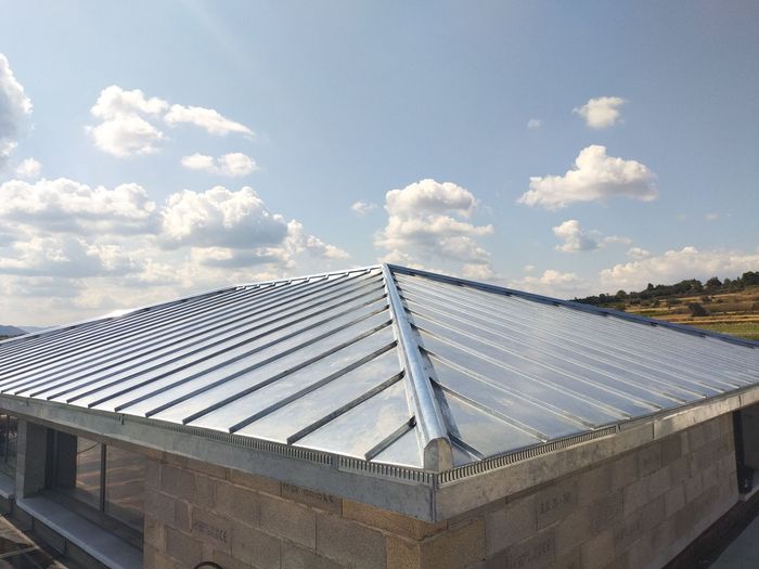 Toiture en tôle ondulée sur un bâtiment bas en béton sous un ciel bleu nuageux