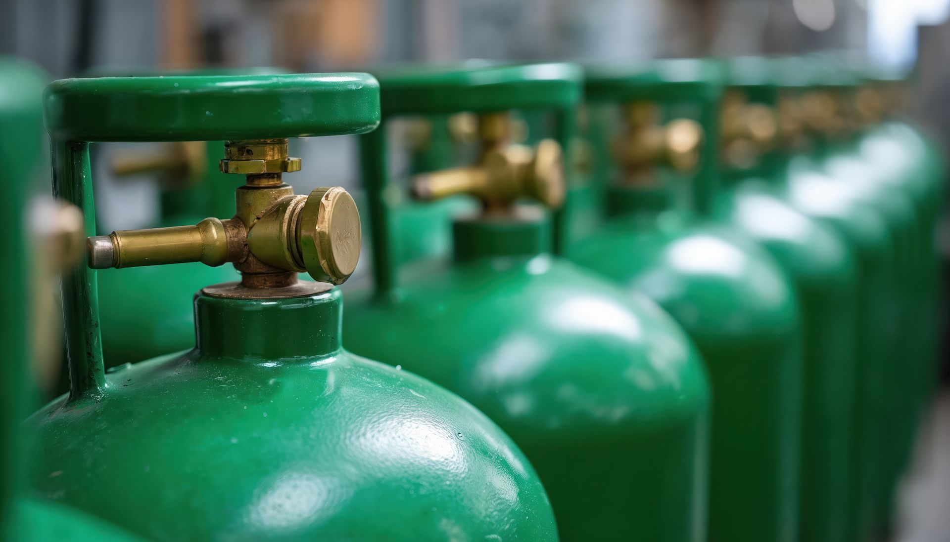 Réservoirs d'oxygène verts alignés, avec des vannes en laiton, probablement dans une installation de stockage.