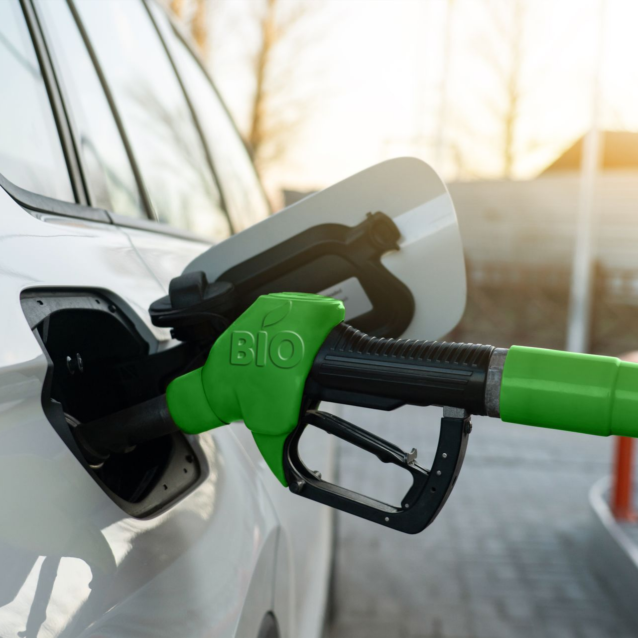 Pompe à carburant bio vert remplissant une voiture blanche.