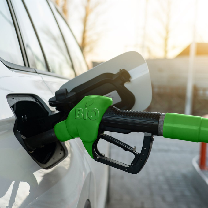 Pompe à carburant bio vert remplissant une voiture blanche.
