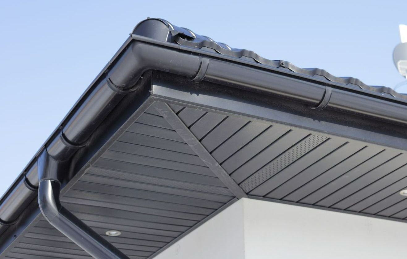 Une gouttière noire avec des planches de rives