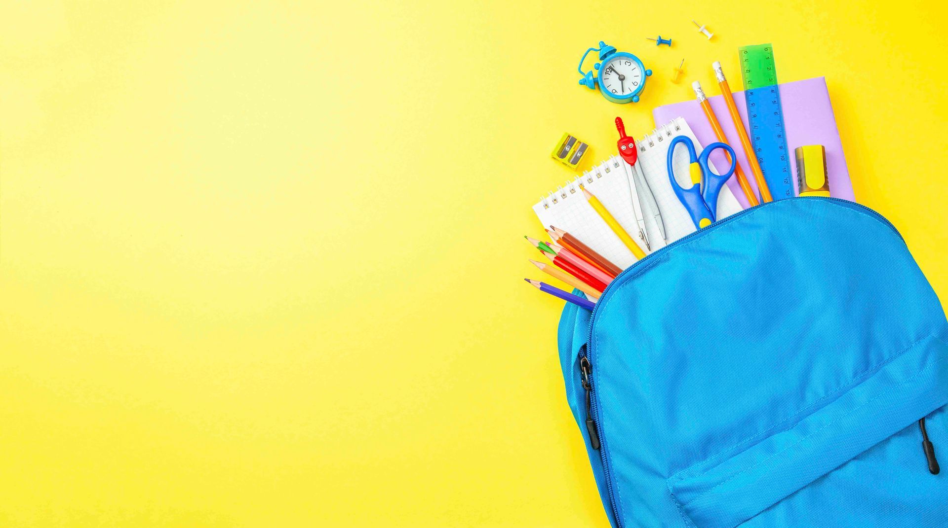 ein blauer Rucksack voller Schulmaterial auf gelbem Hintergrund.