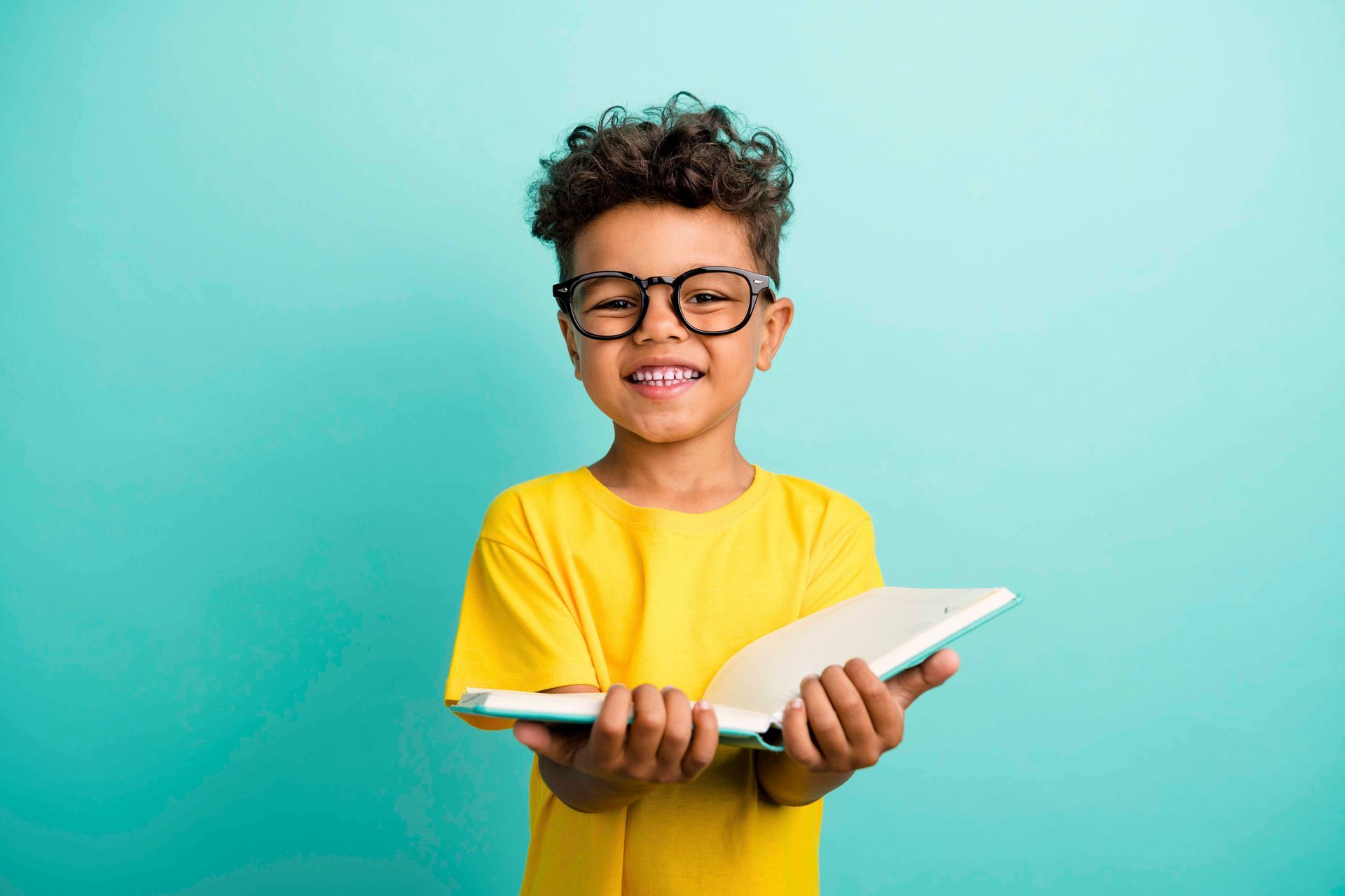 Ein kleiner Junge mit Brille hält ein Buch in den Händen.