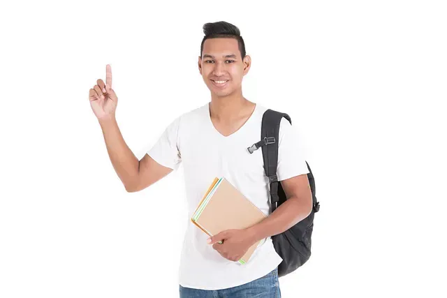 Un joven con una mochila sostiene un libro y señala hacia arriba.