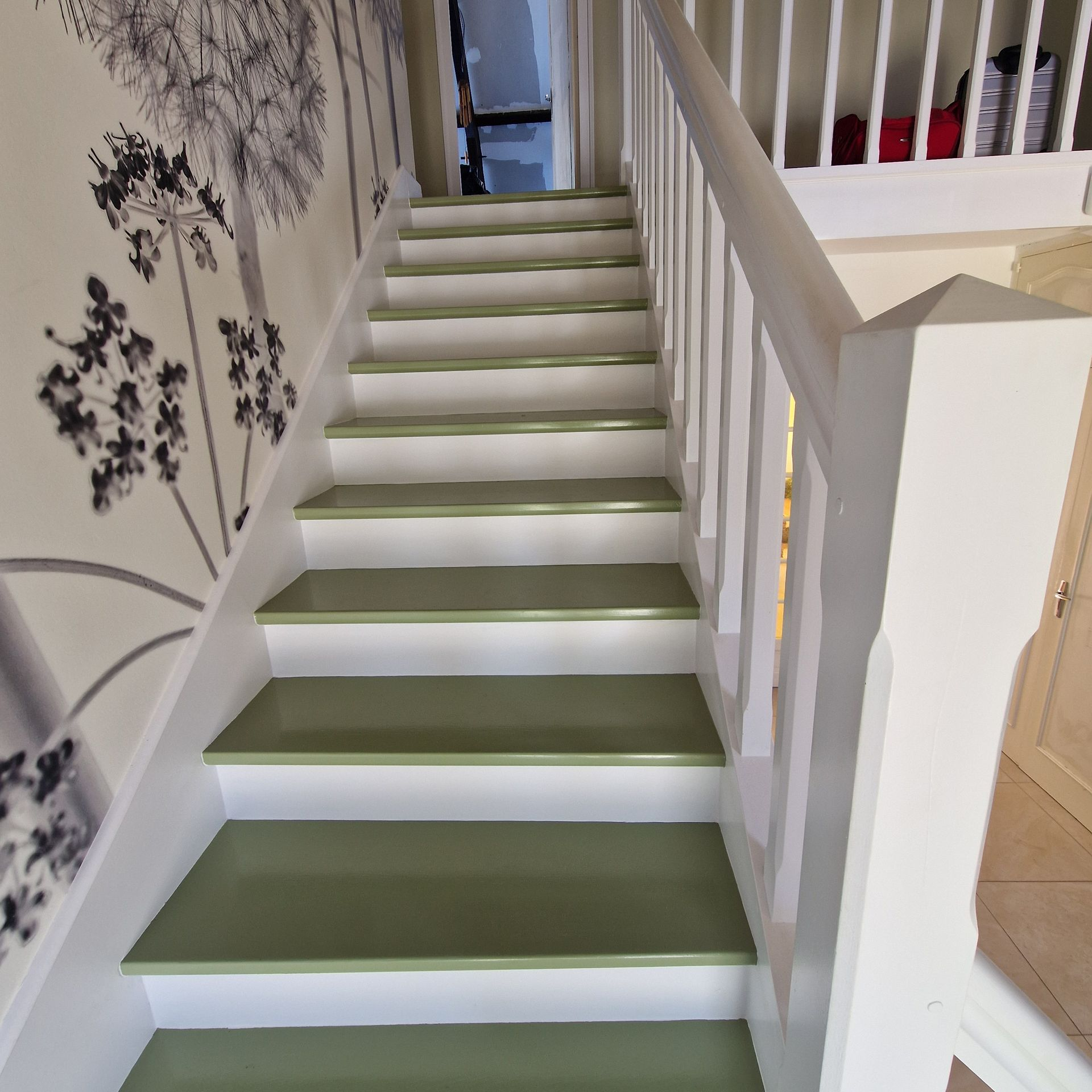 Escalier en bois repeint en blanc avec un pan de mur en papier peint avec des fleurs