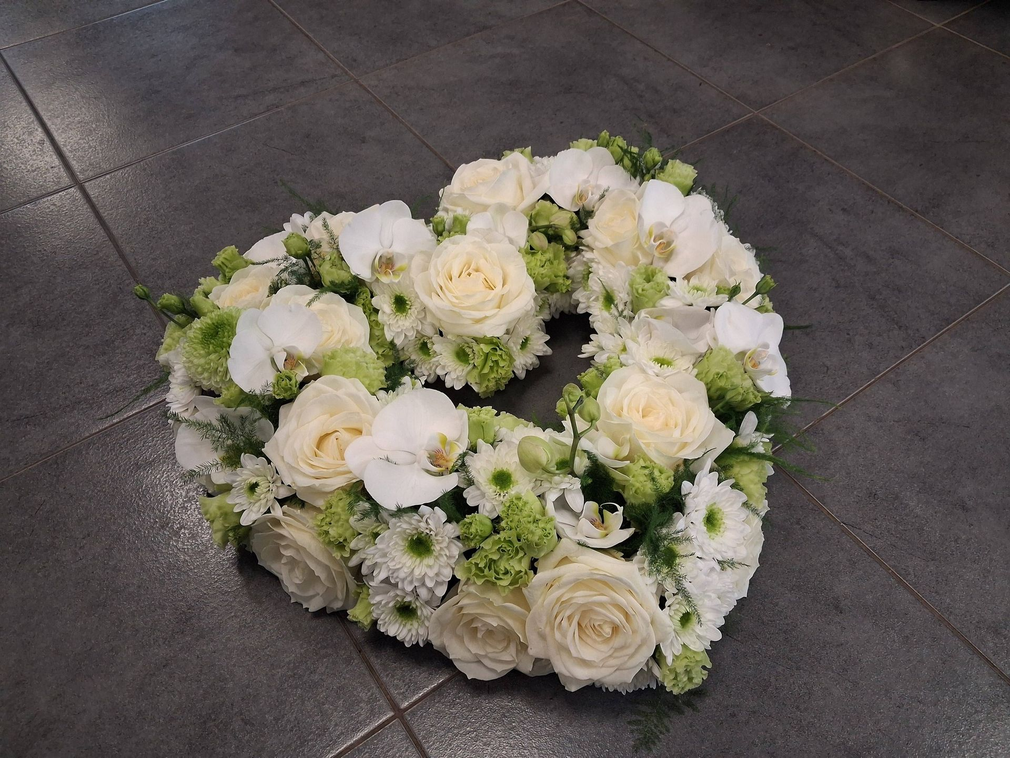 Bouquet fun&eacute;raire compos&eacute; de pivoines blanches et de roses roses, entour&eacute; de feuillages verts.