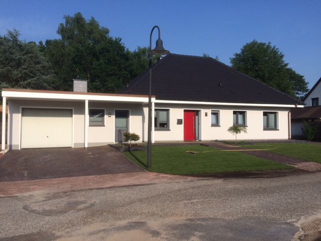 Ein weißes Haus mit einer roten Tür und einem schwarzen Dach