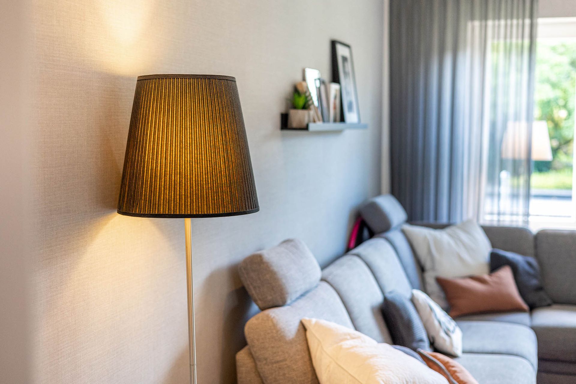 In einem Wohnzimmer steht eine Lampe neben einer Couch.