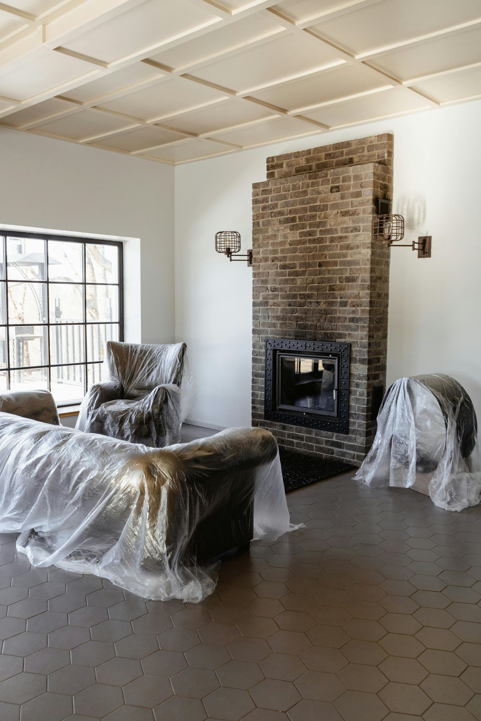 Sala de estar con muebles de madera clara, sofá beige y plantas grandes.