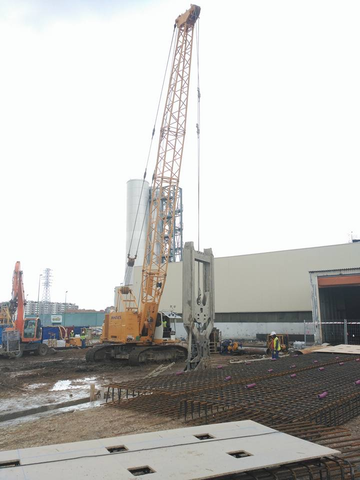 Una gran grúa está levantando un trozo de hormigón en una obra en construcción.