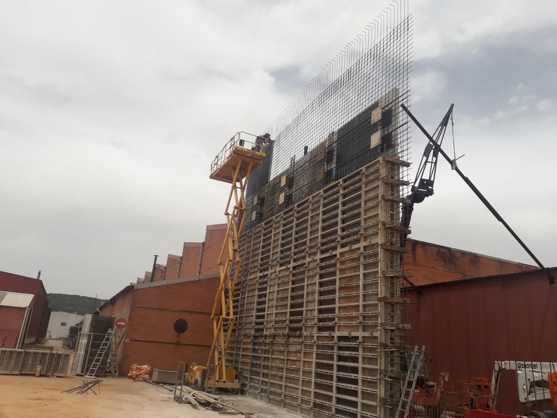 Se está construyendo un gran muro con una grúa al fondo.