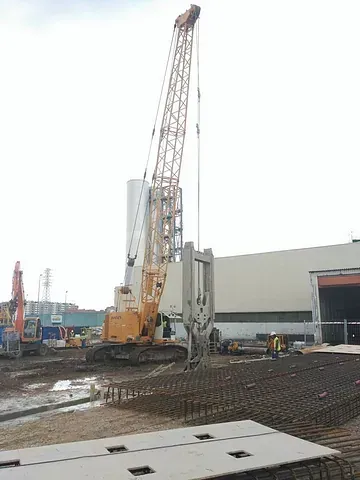 Una grúa grande está trabajando en un sitio de construcción frente a un edificio.