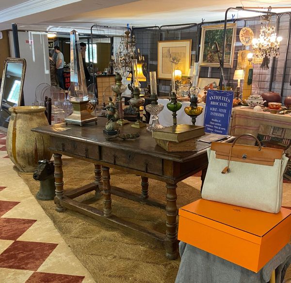 Table ancienne en bois avec lampes et sac à main clair.