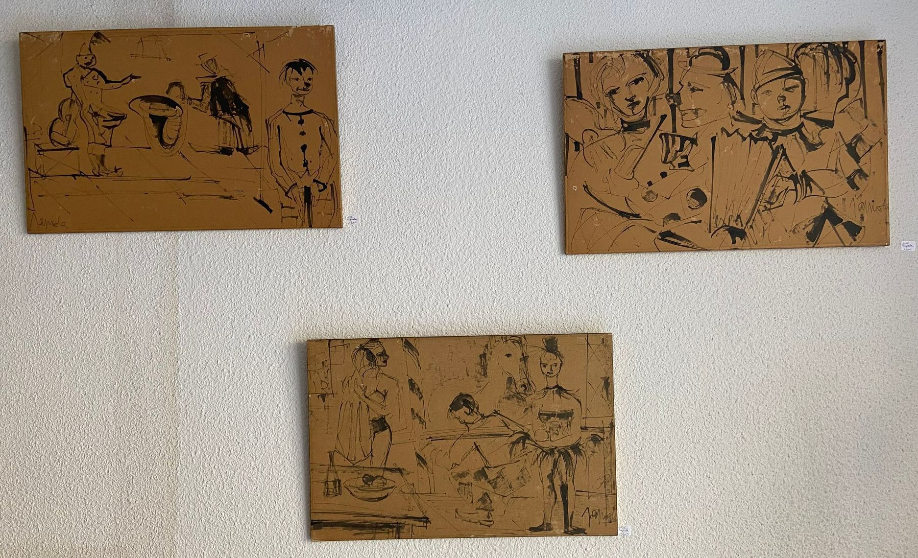Trois gravures murales représentant des scènes de groupe, accrochées sur un mur blanc.