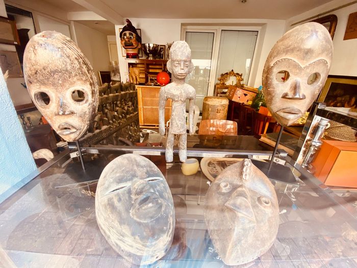 Masques et statuettes africains exposés sur une table en verre.