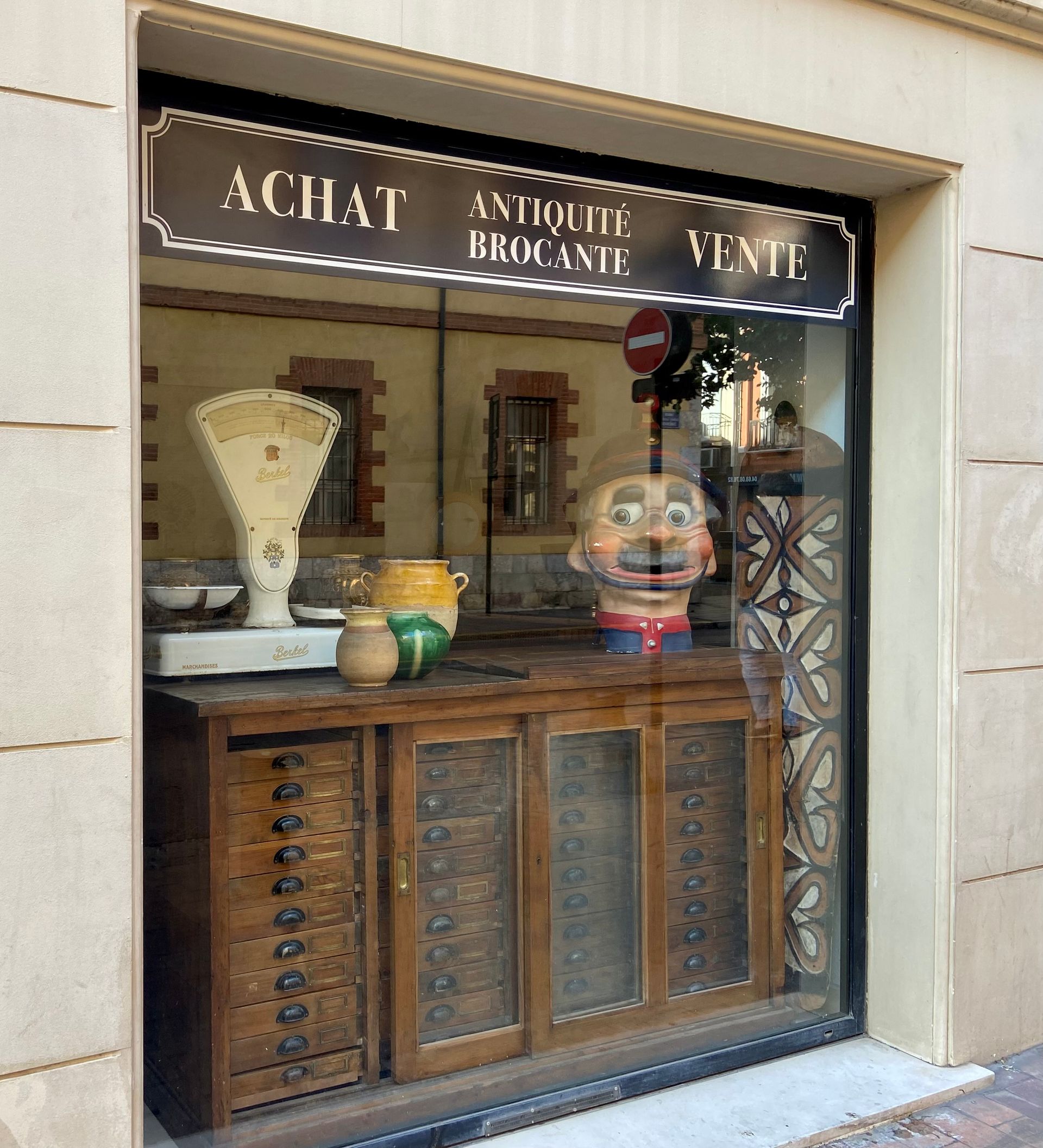  Intérieur d’une boutique avec un comptoir en bois, des étagères et des objets décoratifs en vitrine.