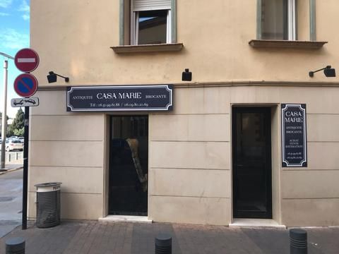  Façade d’un bâtiment nommé Casa Marie Antiquités, avec une entrée et des panneaux de signalisation à proximité.