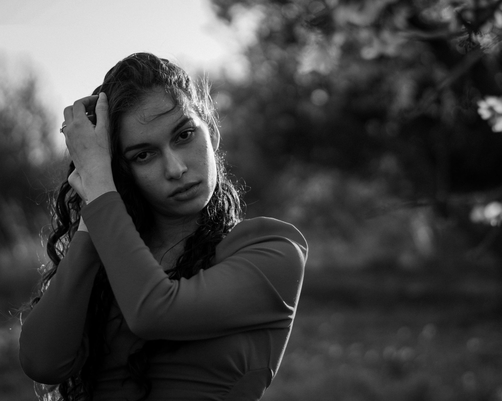 Retrato en blanco y negro de una persona con el pelo mojado, sosteniendo su cabeza al aire libre, con expresión pensativa.
