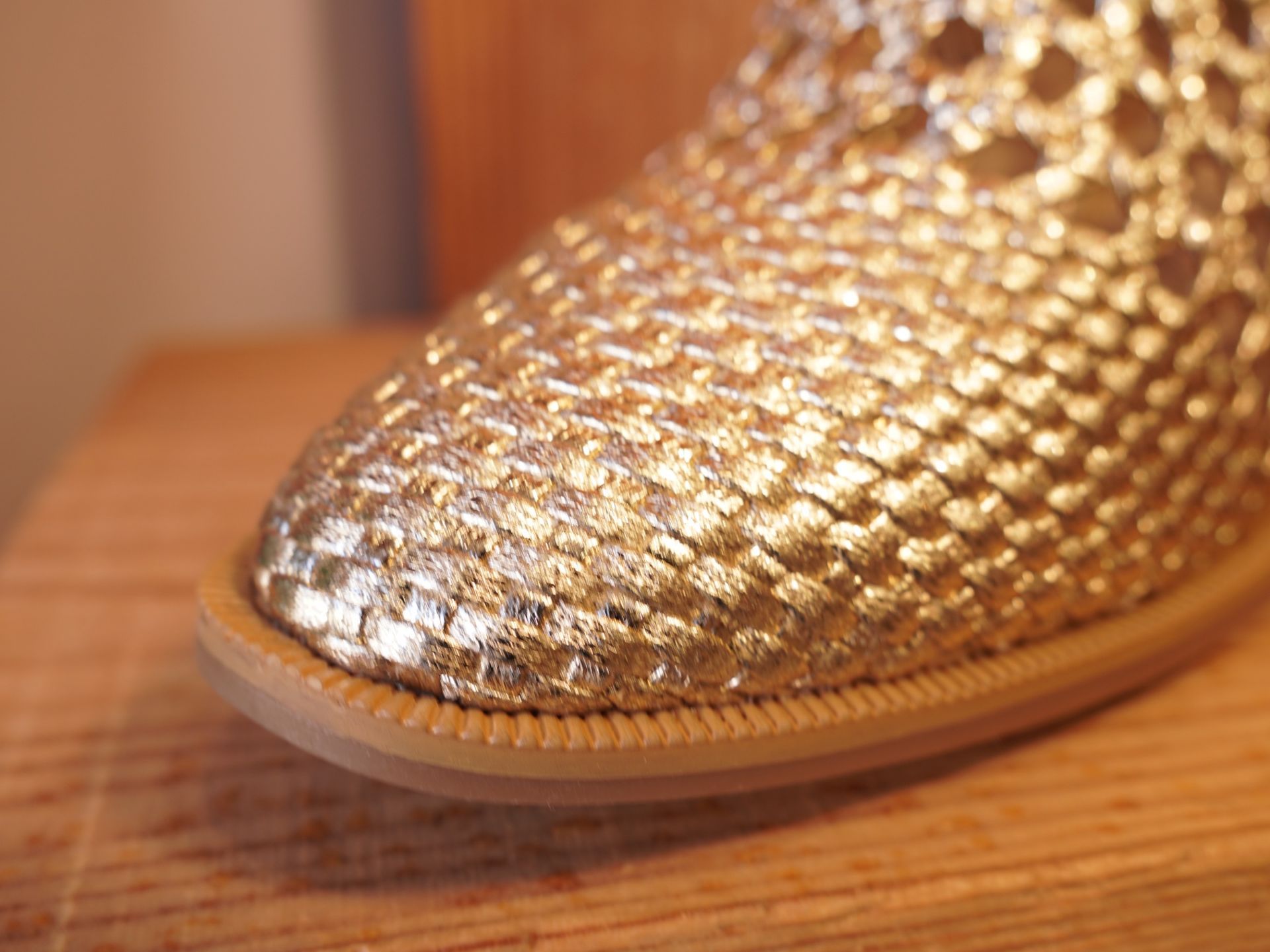 Punta de zapato con lentejuelas doradas sobre un suelo de madera