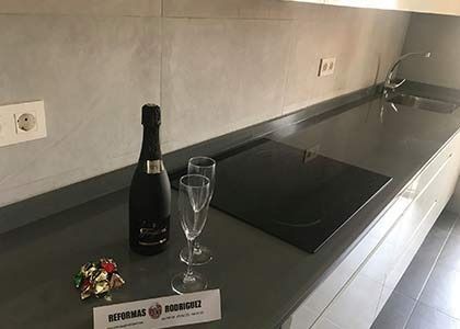 Una botella y dos vasos sobre la encimera de la cocina, junto a la estufa.