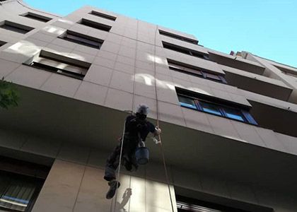 Una persona desciende en rápel por la fachada de un edificio alto usando cuerdas.