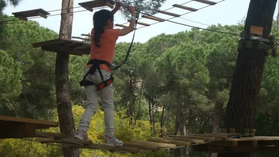 Uma garota está parada em um percurso de cordas na floresta