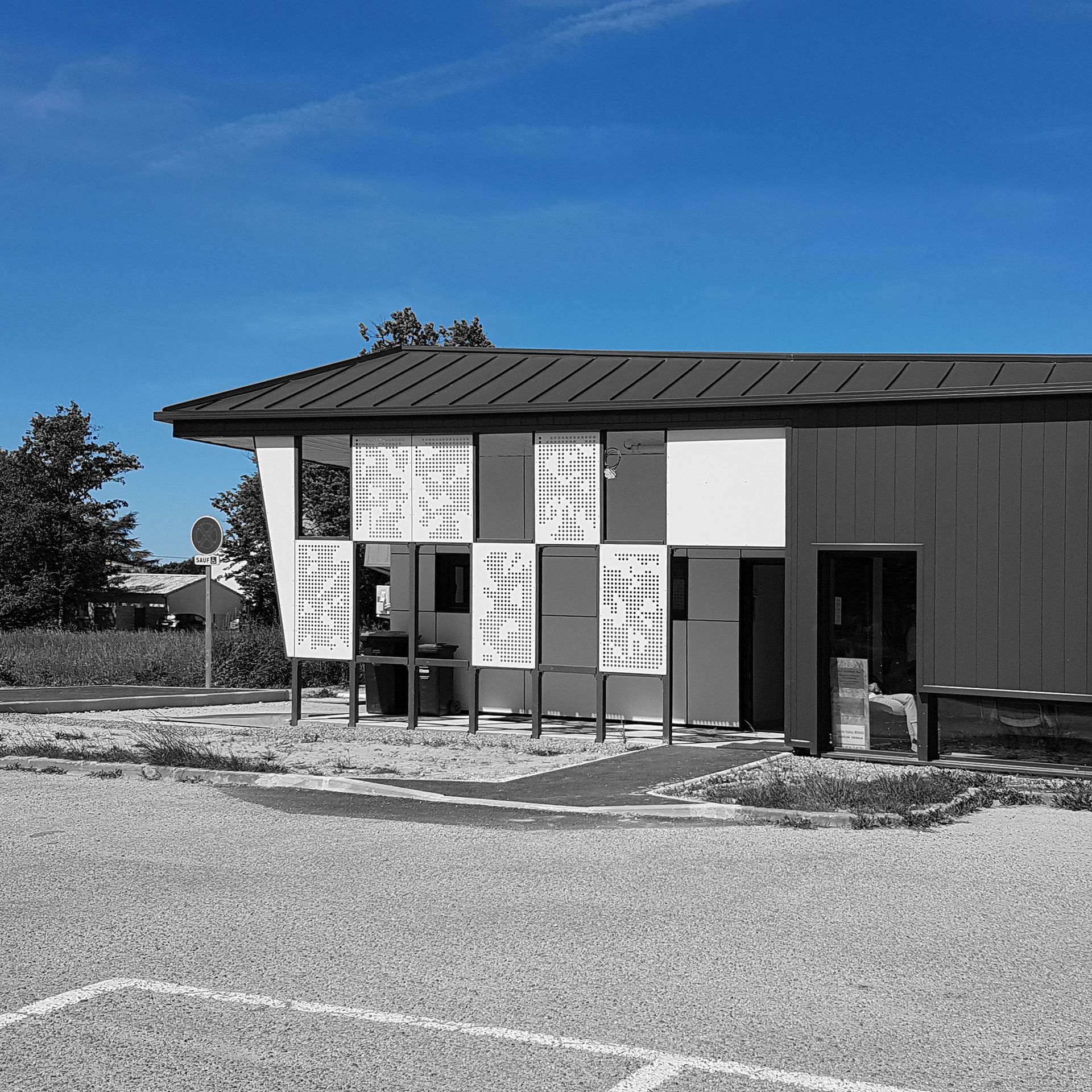 Plaques blanches tenues par une structure en métal devant bâtiment