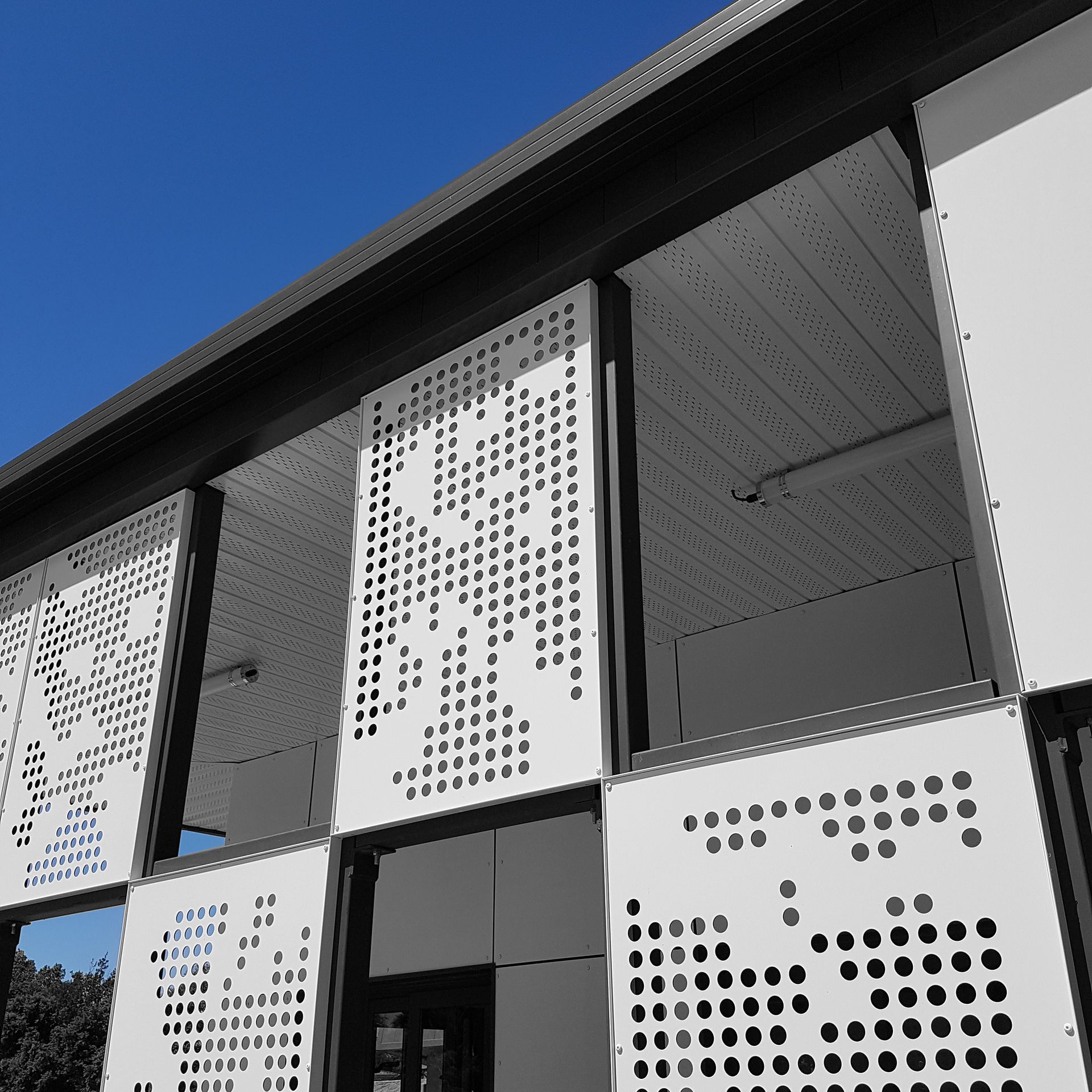 Plaque blanche trouée devant un bâtiment