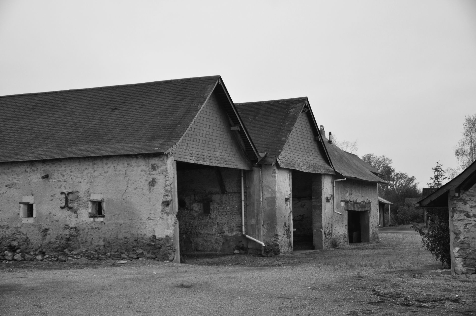 Photo en noir et blanc d'un corps de ferme avec toiture noire
