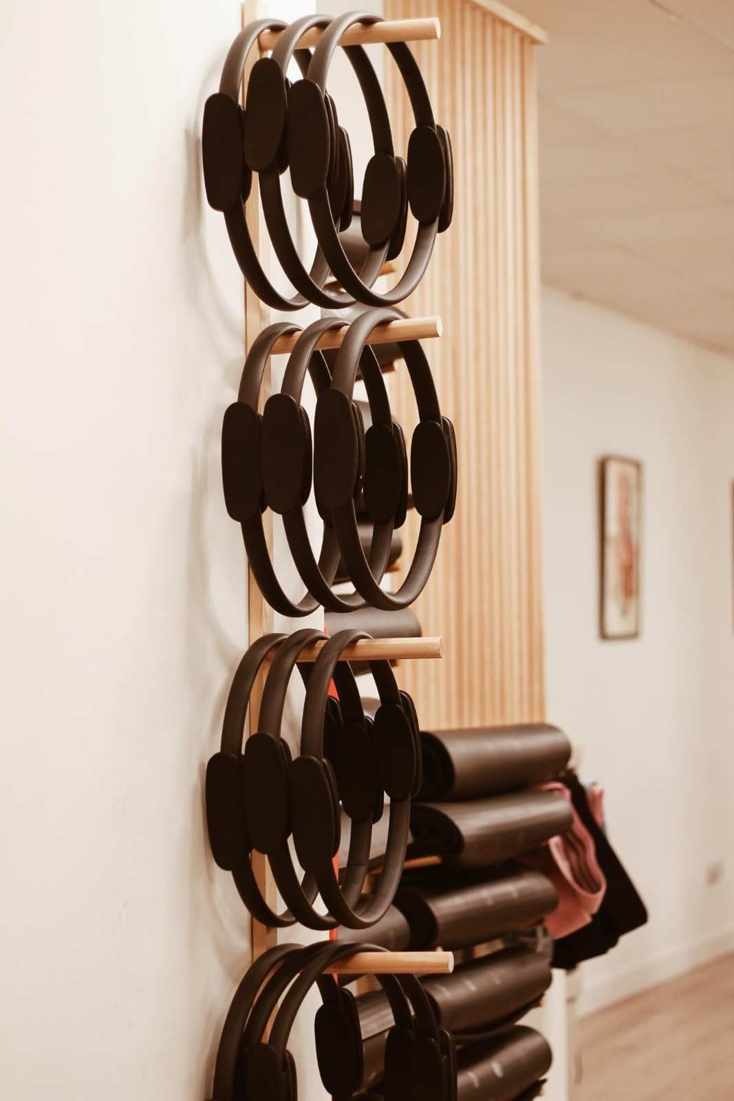 Tazas hechas a mano y telas enrolladas apiladas cuelgan de un estante de madera en la pared de un pasillo.