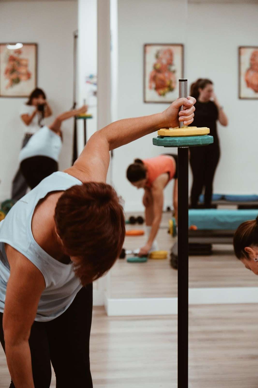 Personas estirándose en un estudio de yoga con espejos y esterillas.