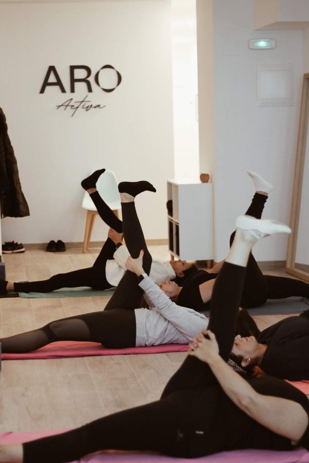Mujer descansando sobre una colchoneta de gimnasia junto a unas mancuernas en un gimnasio.