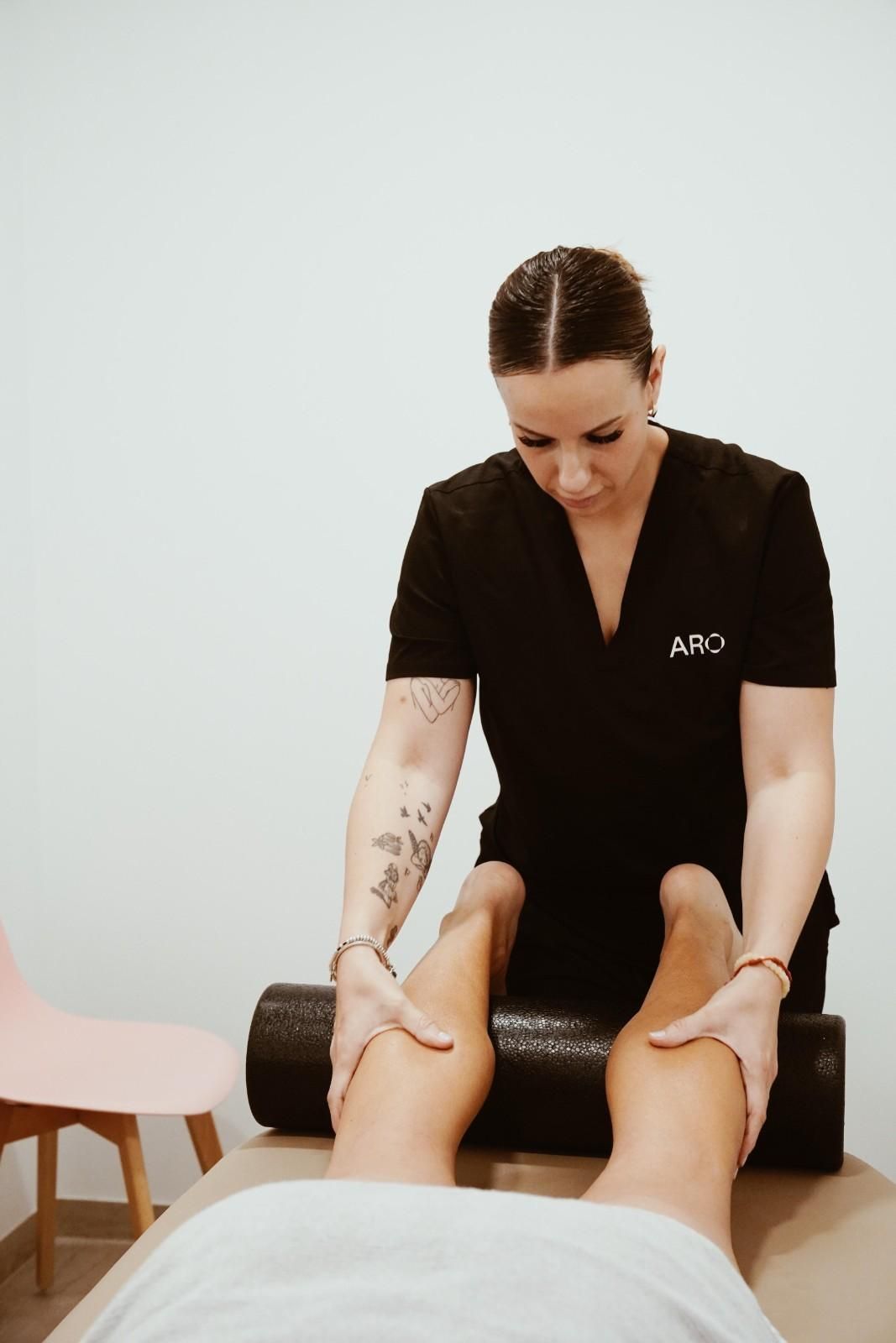 Masajista trabajando en las piernas de un cliente en una luminosa sala de tratamientos de spa.