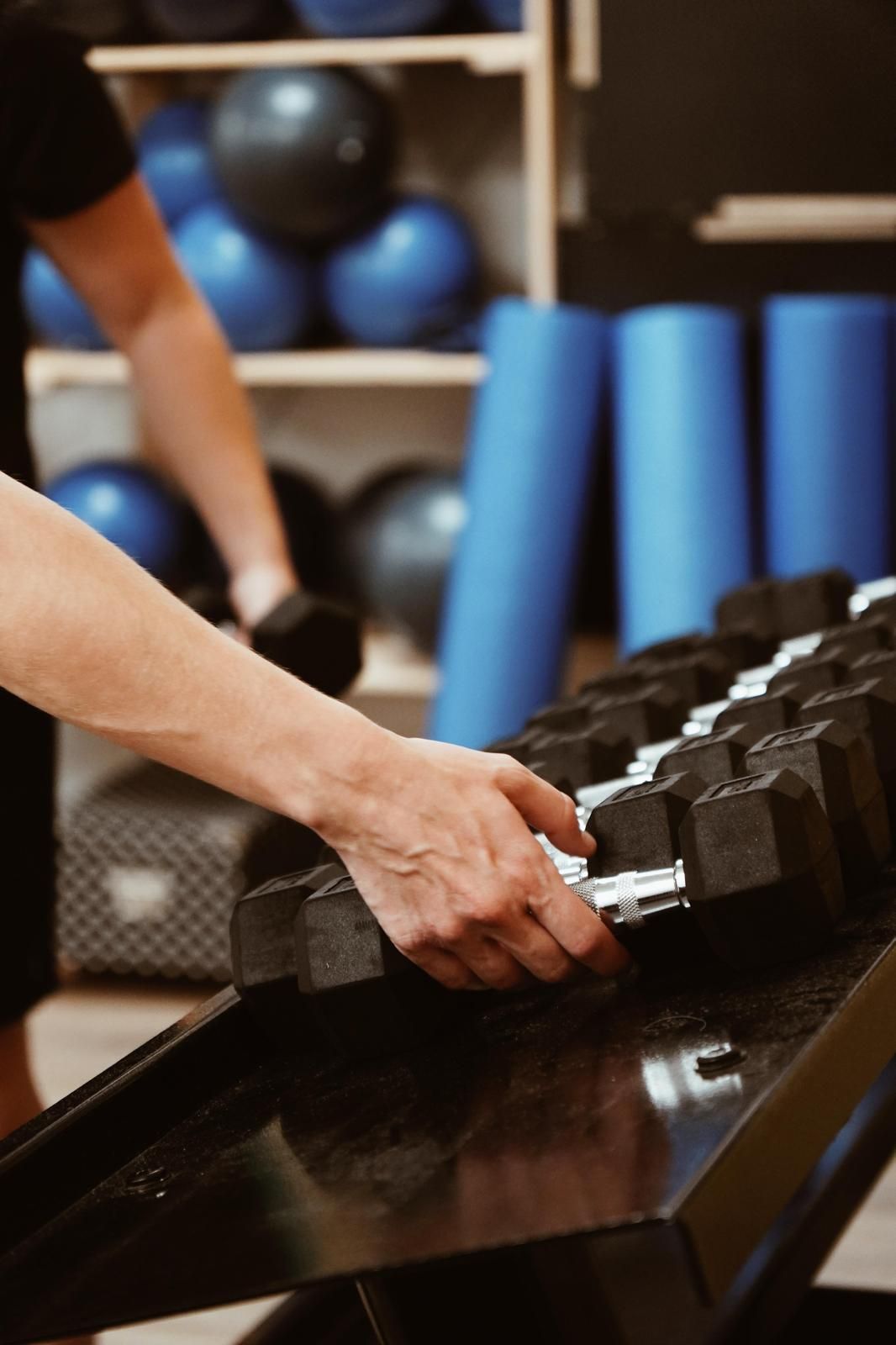 Personas haciendo ejercicio sobre colchonetas en un luminoso gimnasio interior con espejos y decoración.