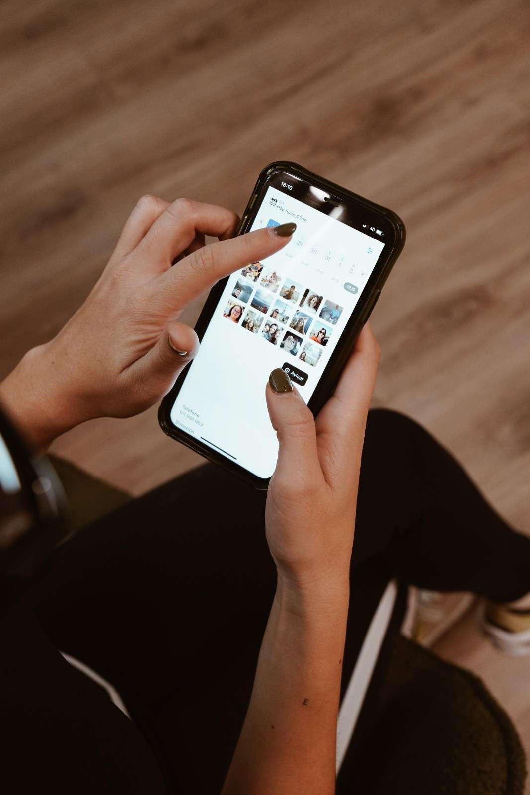 Manos usando un teléfono inteligente con una cuadrícula de fotos en la pantalla, vistas desde arriba.