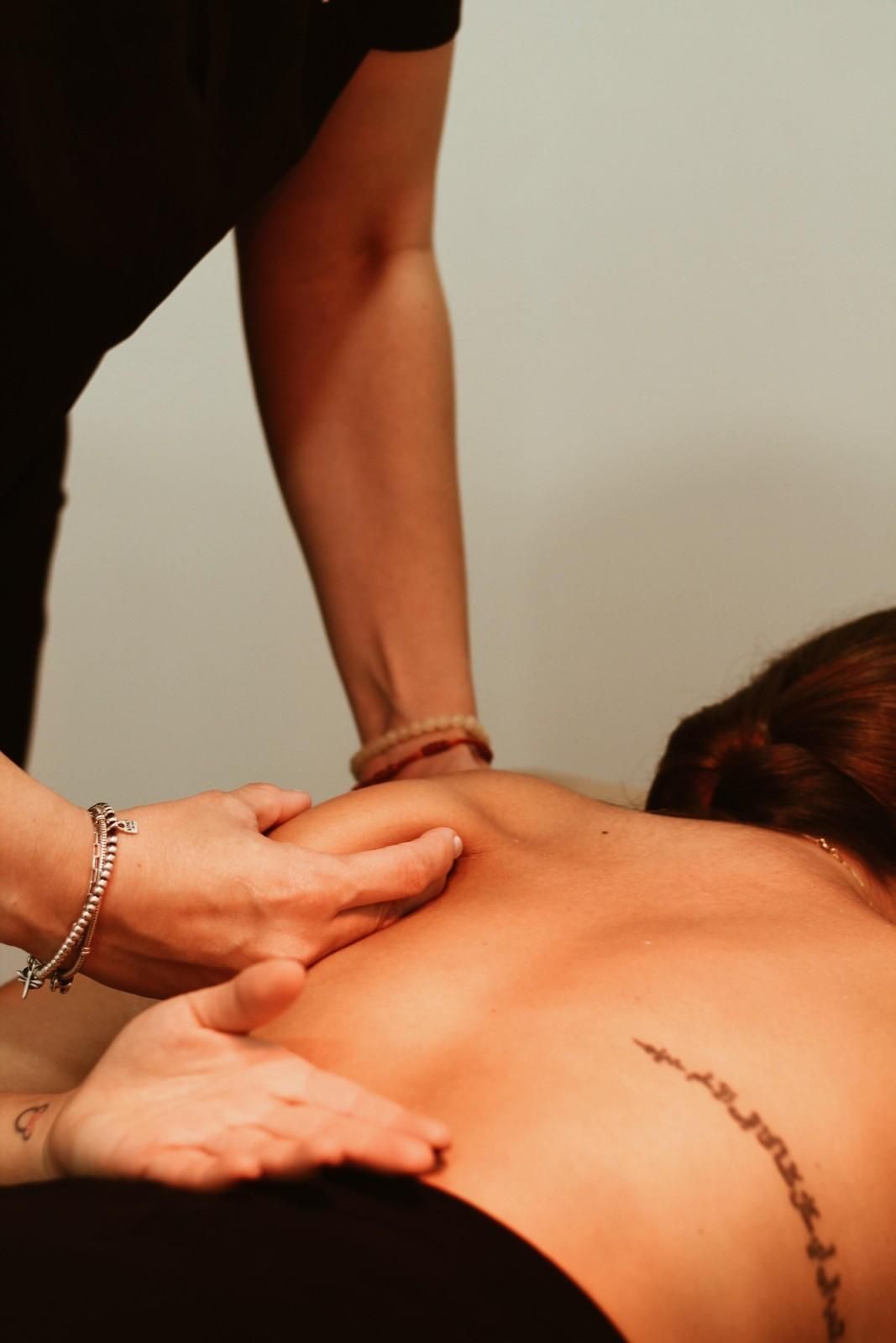 Manos dando un masaje de espalda con aceite en un ambiente de spa.