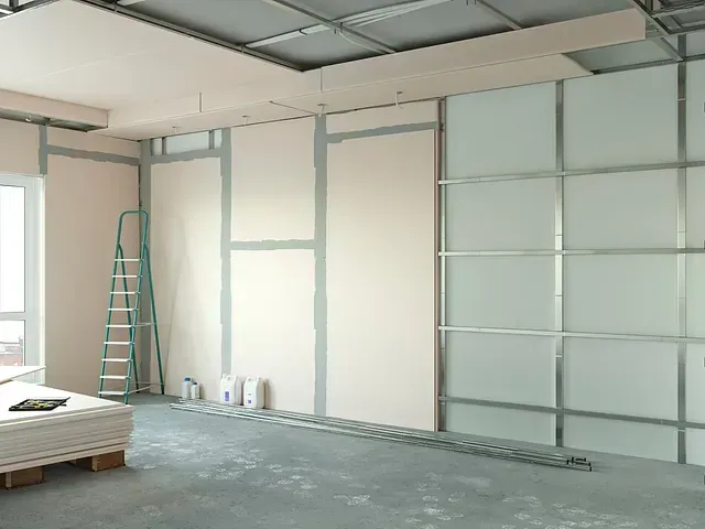 Una habitación en construcción con una escalera y una paleta de paneles de yeso.