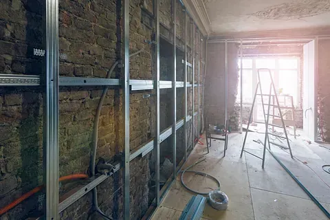 Se está remodelando una habitación con paredes de ladrillo y una escalera.