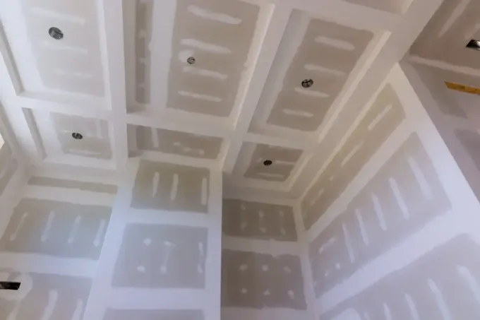 Habitación interior con drywall instalado en paredes y techo, presentando paneles empotrados.