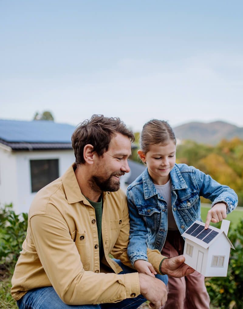 Fillette montrant à son père des panneaux solaires sur une petite maquette de maison