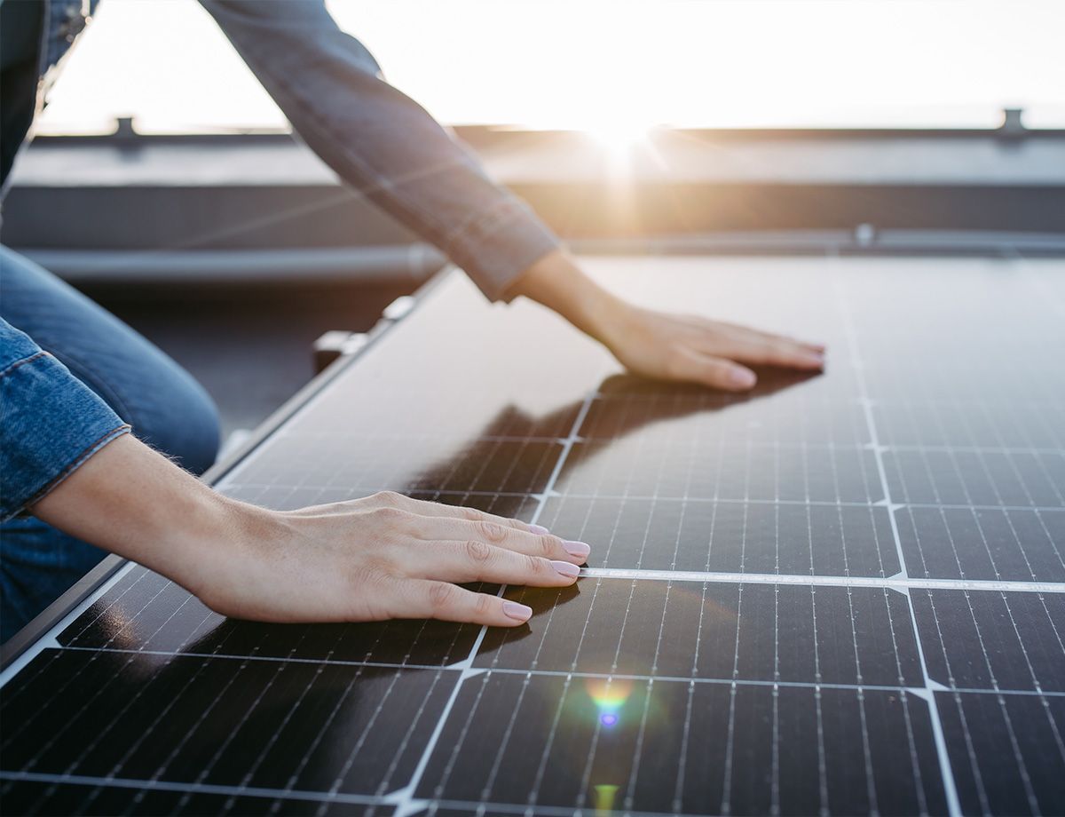 Mains posées sur un panneau solaire éclairé par les rayons du soleil 