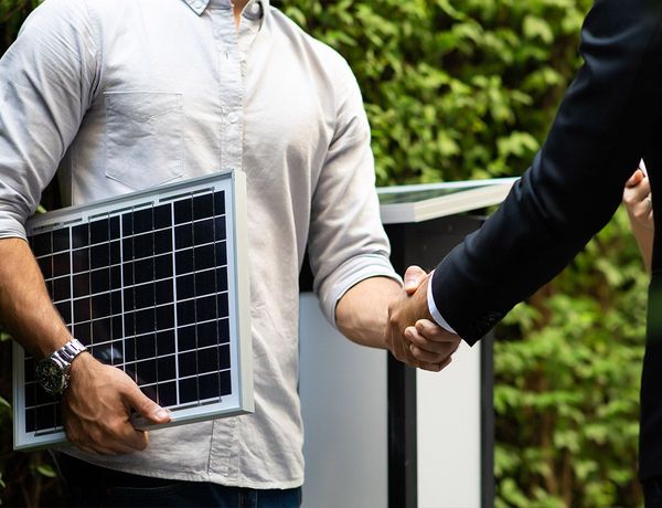 Poignée de main entre deux personnes dont l'une porte un panneau solaire 