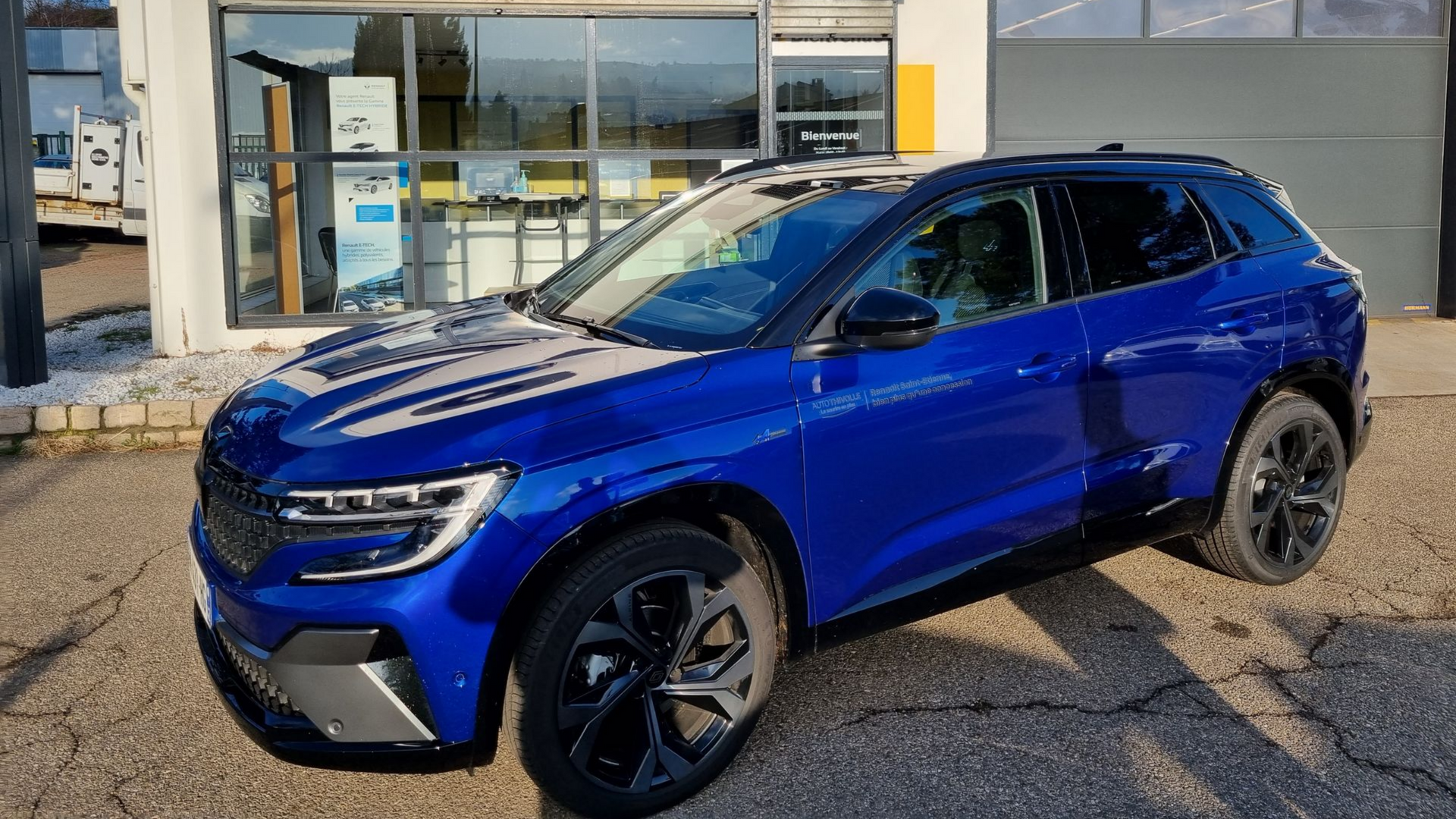 Un SUV bleu devant le garage auto.