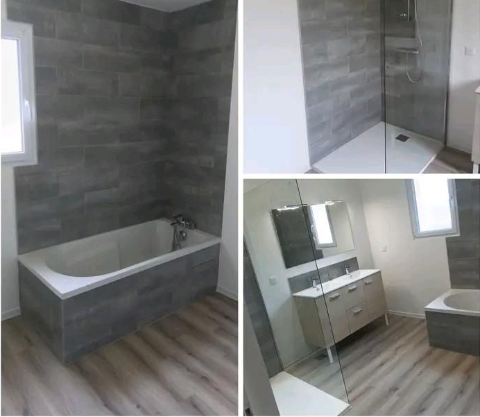 Salle de bains moderne avec carrelage gris, baignoire, douche à l'italienne, meuble-lavabo et fenêtre sur sol imitation bois.