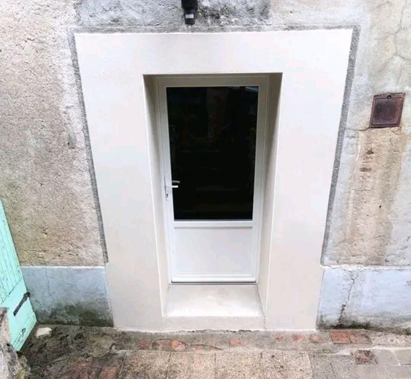 Porte extérieure blanche encastrée dans un mur avec une petite marche devant.