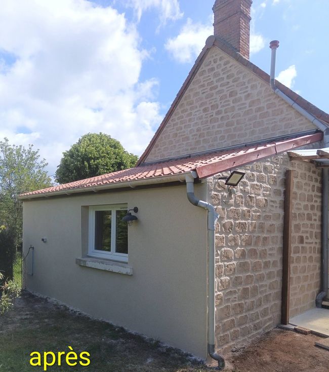 Façade d'une vieille maison en pierre avec une porte et une fenêtre bleu pâle, donnant sur une rue pavée.