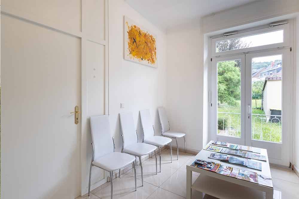 Ein Wartezimmer mit weißen Stühlen und einem Tisch.