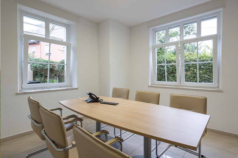 Ein Konferenzraum mit einem Tisch und Stühlen und einem Telefon auf dem Tisch.