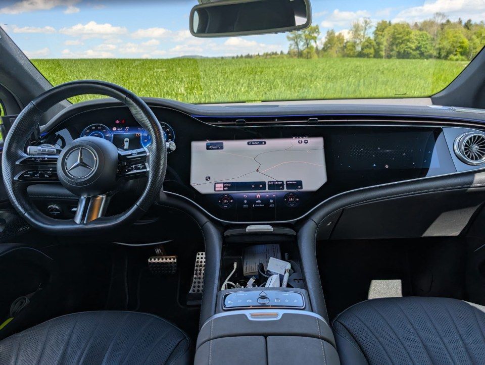 Mercedes-Interieur mit digitalem Armaturenbrett und Blick auf grüne Felder durch die Windschutzscheibe