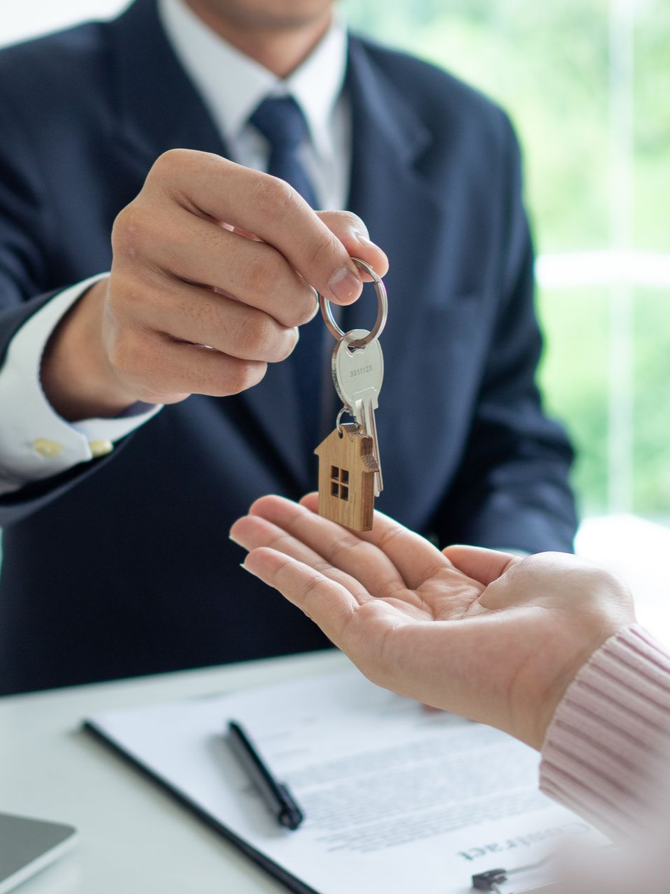 Une personne en costume remet des clés à une autre personne.